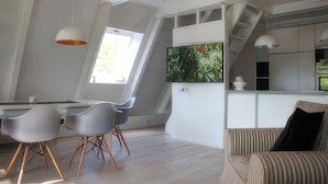 A modern kitchen with a TV, a dining area with chairs, and a staircase. - Modern, cozy vacation home with a fireplace, sauna, and large garden (Winsen (Aller))