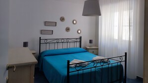 Quarto com cama, mesas de cabeceira, luminária pendente e decorações nas paredes.