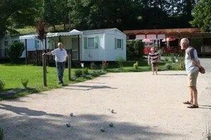 En grusvej fører hen til et hus med en overdækket veranda, og i baggrunden ses en campingvogn.
