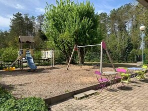 A playground with a swing set, slide, and climbing structure. - Camping 3 étoiles - Piscine  - ccbgdgg (Arc-et-Senans)