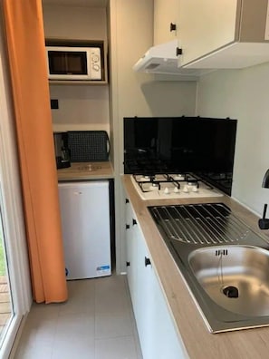Une cuisine compacte équipée d’un four à micro-ondes, d’une cuisinière et d’un évier.
