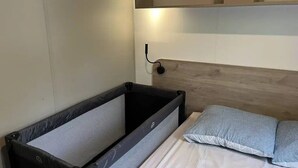 Une petite chambre avec un lit superposé, une petite table de chevet et une étagère fixée au mur.