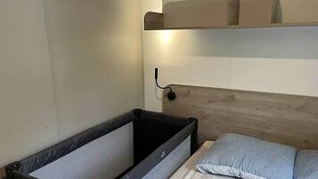 A compact room with a bunk bed, a small bedside table, and a wall-mounted shelf.
