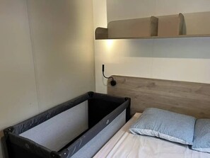 Ein kleines Zimmer mit einem Etagenbett, einem Nachttisch und einem an der Wand befestigten Regal.