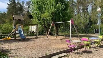 A playground with a swing set, slide, and climbing structure.