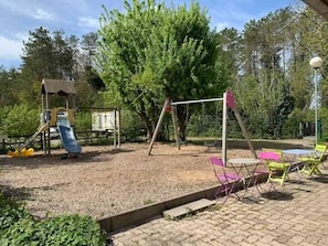 Ein Spielplatz mit Schaukeln, einer Rutsche und einer Klettergerüst.