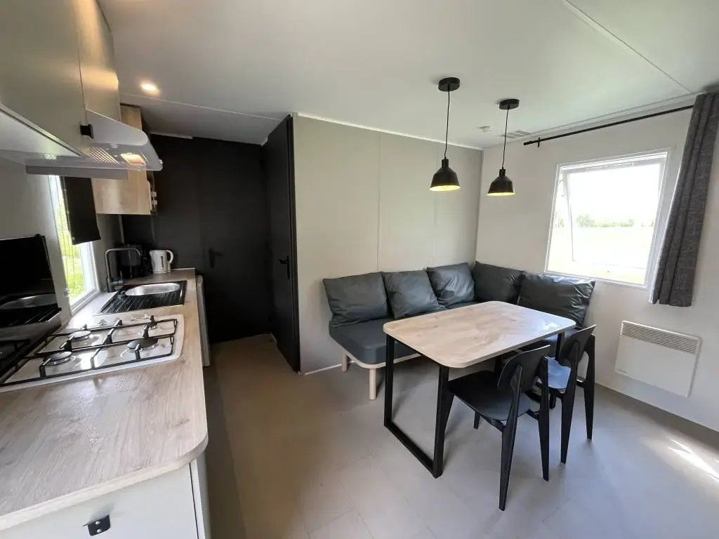 Una cocina compacta con estufa a gas, cafetera y comedor con mesa y sillas.