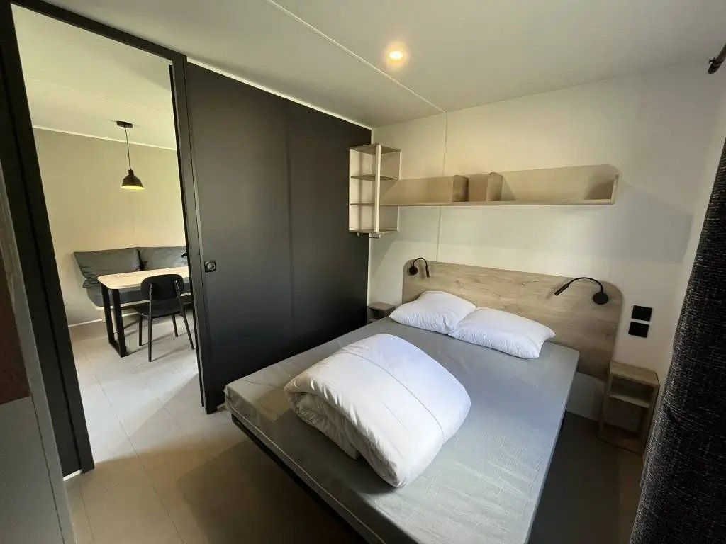 Une chambre à coucher moderne avec un lit, des tables de chevet, un bureau et une chaise.