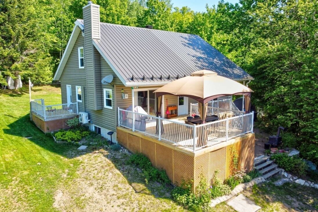 A two-story house with a covered porch and a fenced deck.