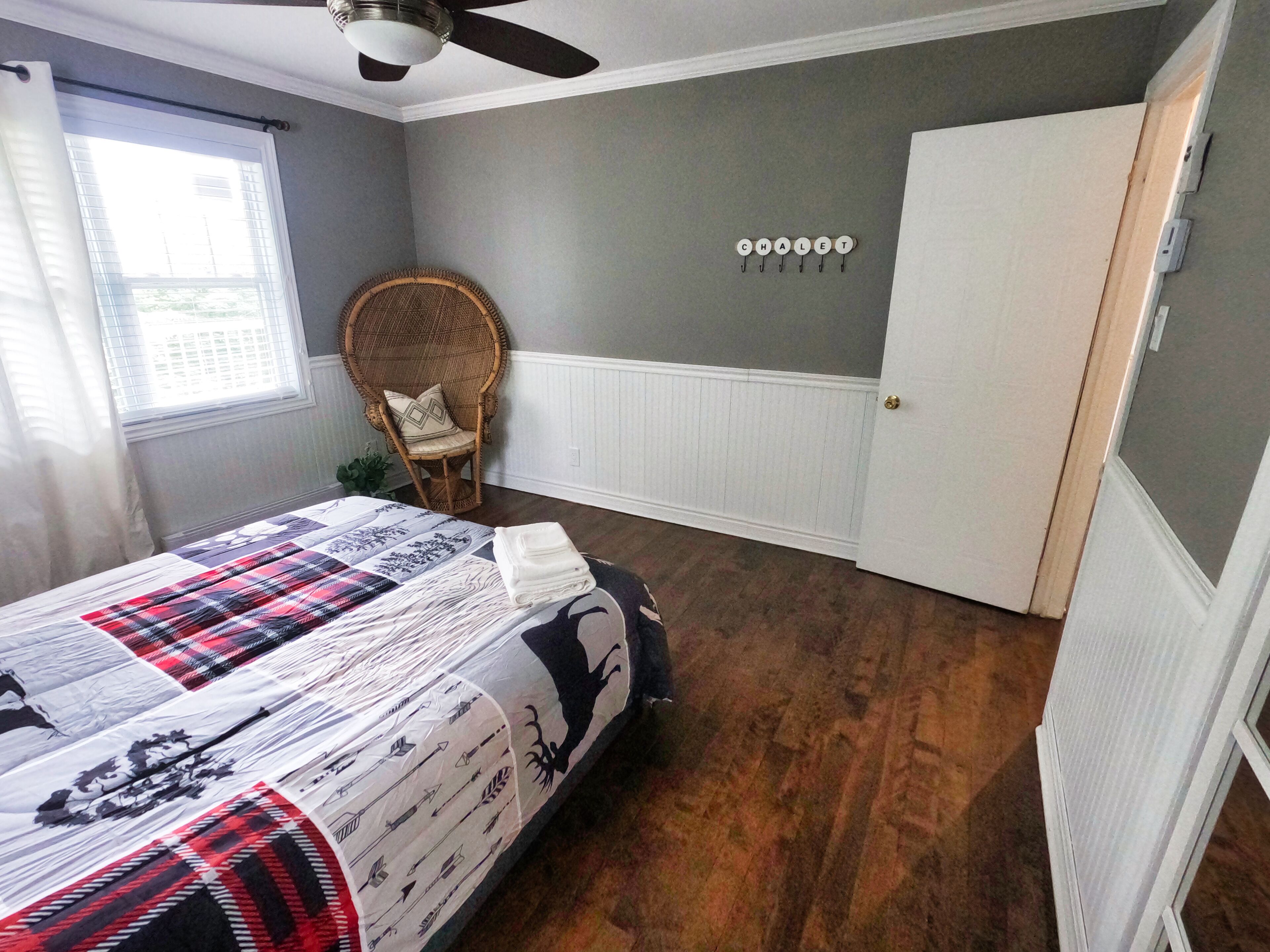 A bedroom with a bed, a chair, a door, and a wall with a word spelled out in letters.