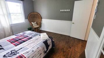 A bedroom with a bed, a chair, a door, and a wall with a word spelled out in letters.