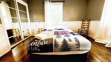 A bedroom with a bed, a window with curtains, a chair, and a shelf.
