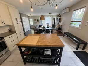 Una cocina moderna con armarios blancos, una mesa de comedor de madera y un banco negro.
