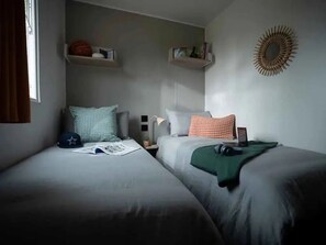 A bedroom with two beds, a nightstand, and wall-mounted shelves. - Camping 3 étoiles - Piscine  - ccbgdh0 (Arc-et-Senans)