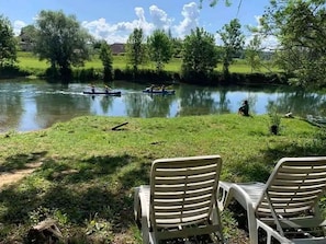 Une vue sur la rivière, avec des chaises et une étendue d’eau paisible.