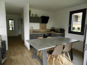 Een moderne keuken met een centraal eiland, een eethoek met stoelen, en uitzicht op buiten.