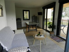 A modern living room with a sofa, a dining table, and a small coffee table. - Chalet - Piscine - ccbfiia (Bollène)