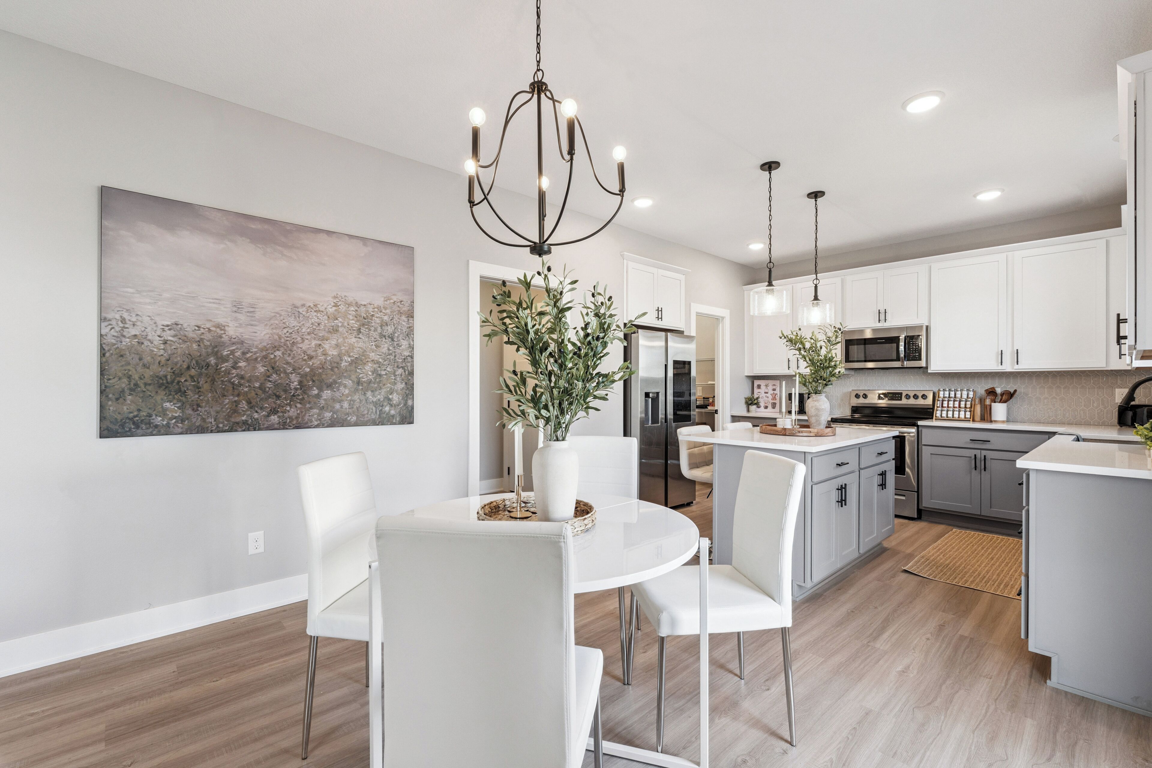 A modern kitchen with white cabinets, a central island, and pendant lighting.