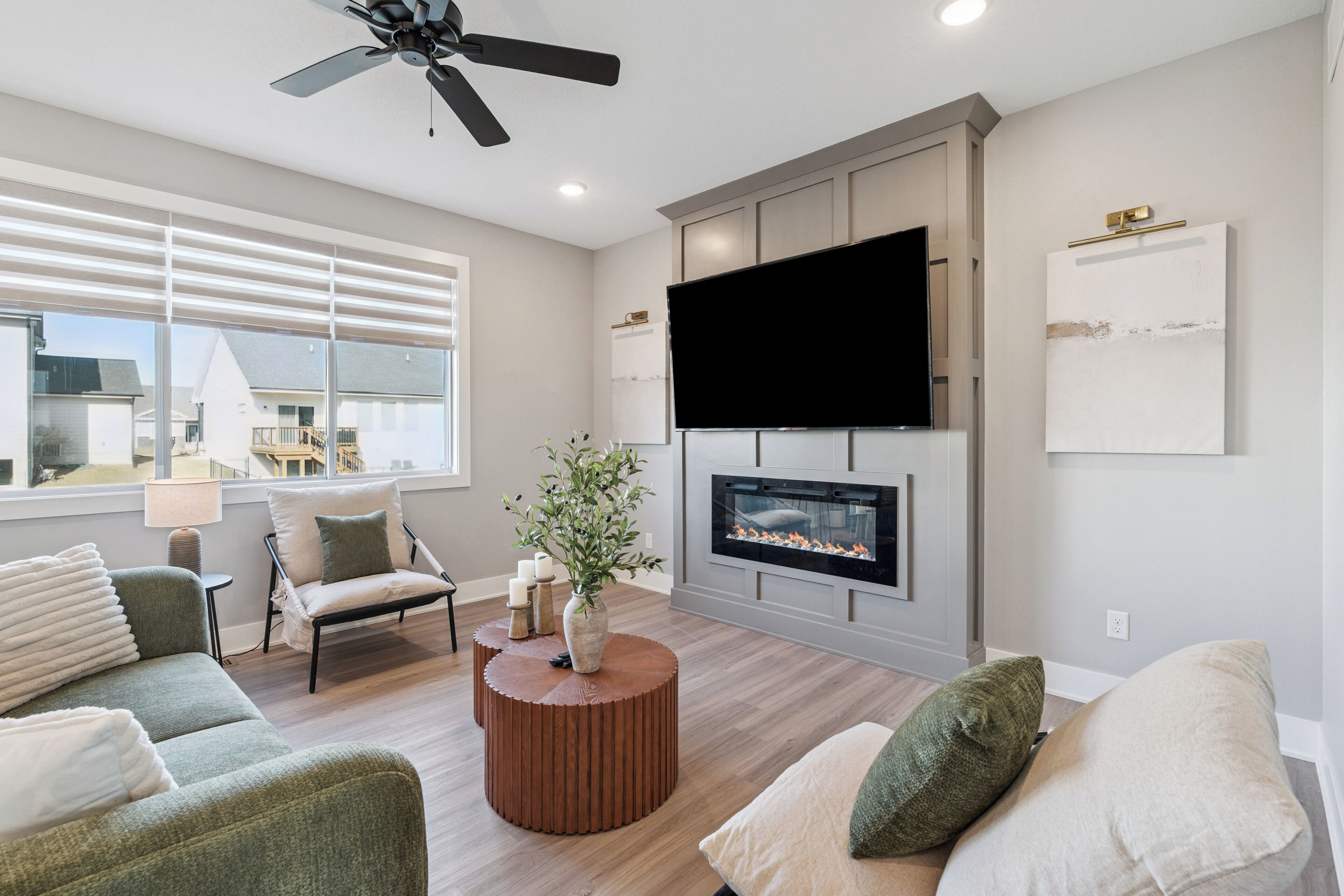 Ein modernes Wohnzimmer mit Kamin, Flachbildfernseher und Deckenventilator.
