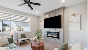 Una sala de estar moderna con chimenea, televisor de pantalla plana y ventilador de techo.