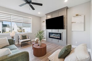 Ein modernes Wohnzimmer mit Kamin, Flachbildfernseher und Deckenventilator.