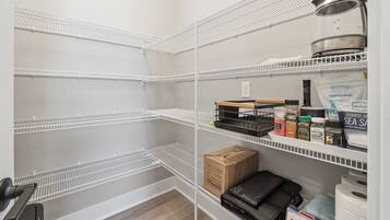 Un espace de stockage équipé d’étagères métalliques, d’une bouilloire et de divers produits emballés.
