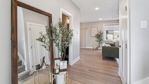 Un pasillo con un espejo de marco de madera, una pequeña mesa con una planta en maceta y una escalera que lleva a otra habitación.