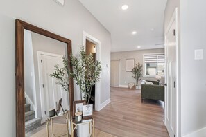 Ein Flur mit einem spiegelnden Holzbettrahmen, einem kleinen Tisch mit einem Blumentopf und einer Treppe, die in einen anderen Raum führt.