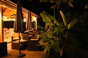 An outdoor seating area with tables and chairs, surrounded by plants. - Camping 3 étoiles - Piscine  - ccbgcfa (Puy-l'Évêque)