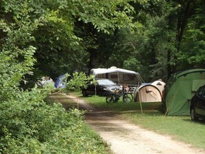 A campsite with a dirt path, a green tent, and a recreational vehicle. - Camping 3 étoiles - Piscine  - ccbgcfa (Puy-l'Évêque)