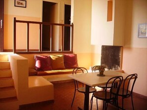 A cozy room with a sofa, a table, and chairs. There is a window with blinds and a picture frame on the wall. - Camping 3 étoiles - Piscine  - ccbgcfa (Puy-l'Évêque)