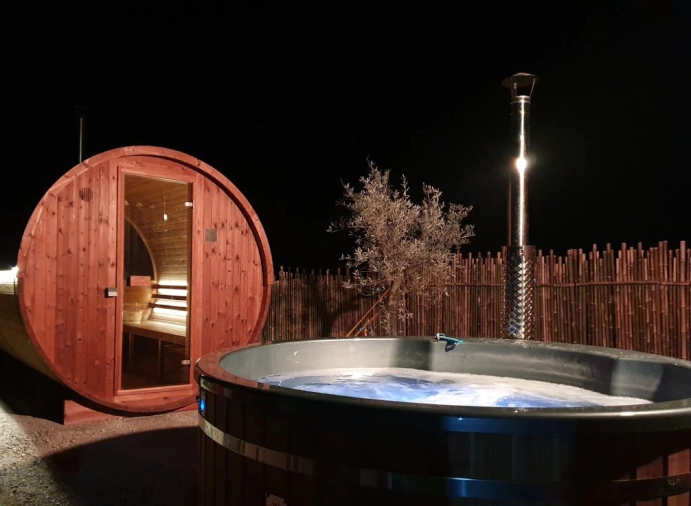 A wooden cabin with a glass door and a hot tub in front.
