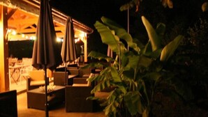An outdoor seating area with tables and chairs, surrounded by plants. - Camping 3 étoiles - Piscine  - ccbgcfb (Puy-l'Évêque)