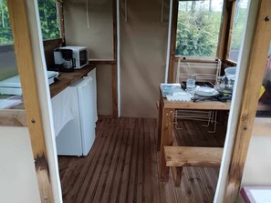 Eine kleine Küche mit Mikrowelle, Kaffeemaschine und einem Kühlschrank.