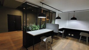 A modern office space with a wooden floor, a white desk, two chairs, a black partition, and pendant lighting. - 57 Spacious 2-bedroom, 2-bathroom Apartment (Johannesburg)