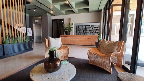 A reception area with wicker chairs, a round table with a vase, and a wooden reception desk. - 57 Spacious 2-bedroom, 2-bathroom Apartment (Johannesburg)