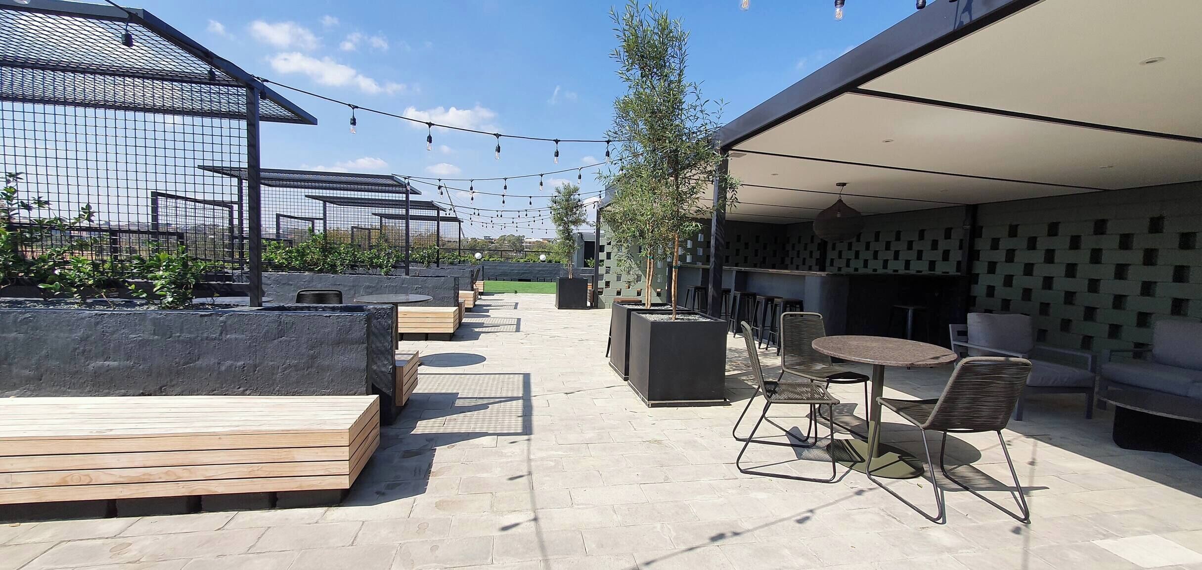 An outdoor patio area with seating, a pergola, string lights, and a covered section with patterned walls.