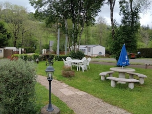 Ein Gartenbereich mit Picknicktisch, Lampe und einer kleinen Gartenhütte.