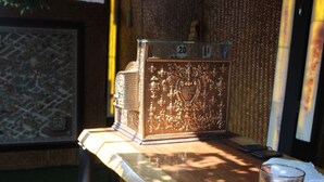 A bar area with a wooden counter, a glass of dark liquid, and a decorative metal box. - Aquí Comes Rico Airport Hostel (Mexico City)
