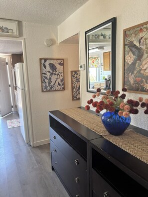 A hallway with a black dresser, a blue vase with flowers, and framed artwork on the walls. - Rood Roost: Spacious 3BR Near Downtown & Grand Junction Adventures (Grand Junction)