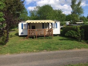 A mobile home with a fenced outdoor area, a satellite dish, and a small porch. - Camping 2 étoiles - ccbgaee (La Tour-d'Auvergne)