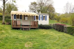 Ein kleines, eingeschossiges Mobilheim mit Veranda und Satellitenschüssel.