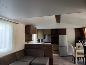 Eine kompakte Küche mit modernen Geräten, ein Essbereich mit Tisch und Stühlen sowie eine Sitzecke mit einer Couch.