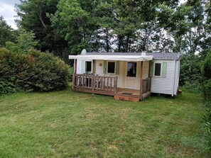 Ein kleines, eingeschossiges Mobilheim mit Veranda und einem umzäunten Deck.