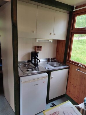 Et kompakt køkken med gaskogeplade, kaffemaskine, vask og køleskab.