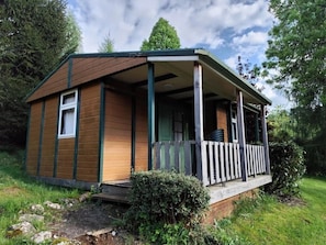A small wooden cabin with a porch, surrounded by greenery. - Chalet 2 étoiles - ccbgafe (La Tour-d'Auvergne)