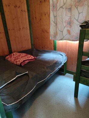 A small, single-occupancy room with a mattress, a pillow, and a wooden chair. - Chalet 2 étoiles - ccbgafe (La Tour-d'Auvergne)