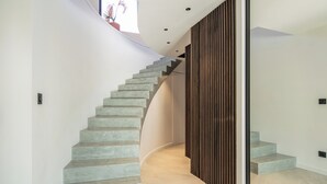 Eine moderne Treppe mit geschwungenem Design, einer Wand aus Holzverkleidung und einem Topf mit einer Pflanze oben.