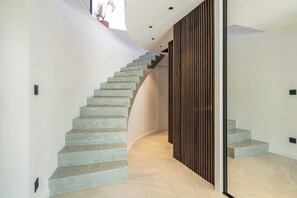 Eine moderne Treppe mit geschwungenem Design, einer Wand aus Holzverkleidung und einem Topf mit einer Pflanze oben.