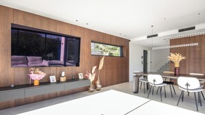 Ein modernes Interieur mit Essbereich, großem Fenster und Wand-Fernseher.